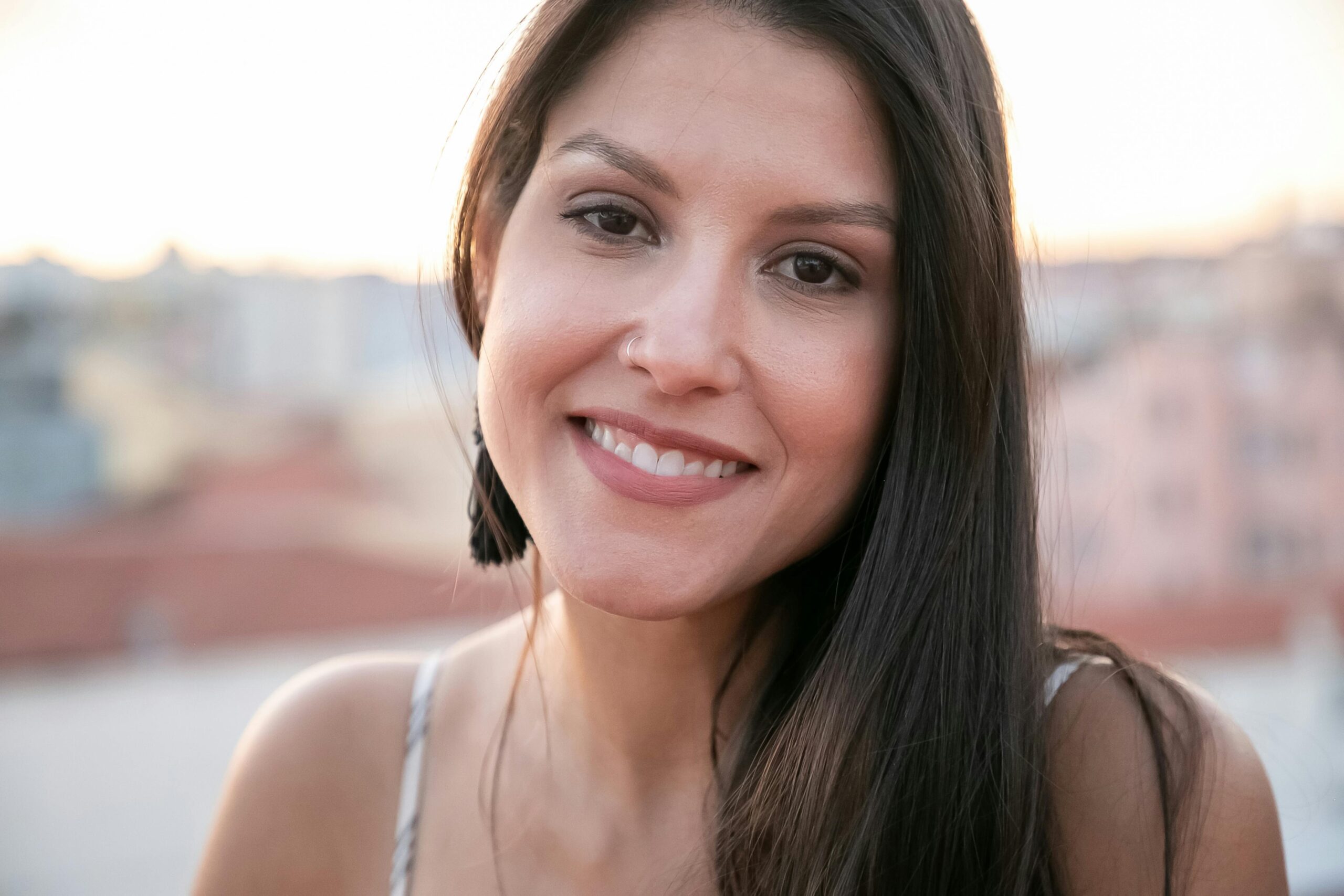 Outdoor portrait of a smiling woman in natural light, captured in Portugal during sunset.